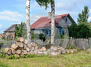 Old rural house with pile of big wooden chocks in front