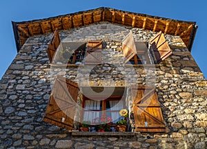 Old rural stone house in the Pyrenees with open wooden windows and precious pots. The light of the late afternoon