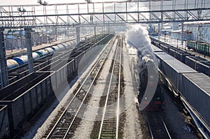 Old Russian steam train rushing , locomotives of other trains standing nearby. Siberia, Russia