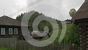 Old Russian village with its old wooden houses and green juicy grass on meadows.