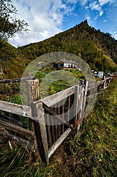 Old Russian village in Siberian woods with wooden gate and fence