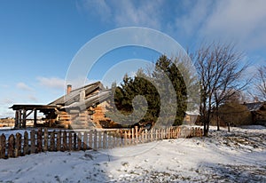 An old Russian wooden hut. Winter landscape with a traditional Russian log house.