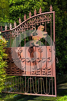 Old rust color iron gate with lion emblem for protection and scroll work in Bali Indonesia