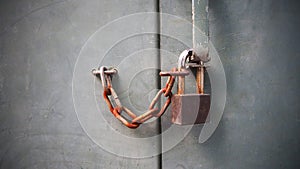 Old rust lock key with chain on grey cement wall. Security concept