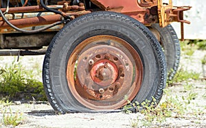 Old rusted abandoned tractor wheel with a flat tire. Very antique tire made in France