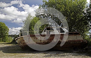 Old rusted boat on the shore near trees