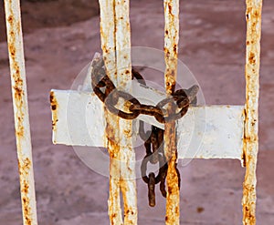 Old rusted chain locking deteriorating metal gate