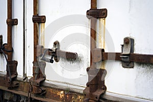 Old rusted door closing mechanism of the semi trailer with digit