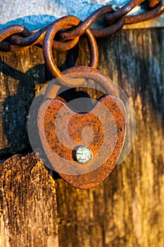 Old rusted heart shaped padlock on a loop chain