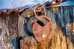 Old rusted heart shaped padlock on a loop chain