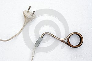 Old rusted immersion heater on a white background.
