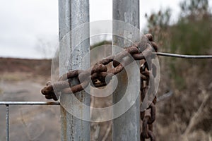 Old rusted iron chain on a metal gate