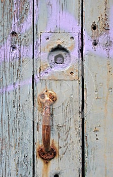 Old rusted iron door handle on a green painted wooden door