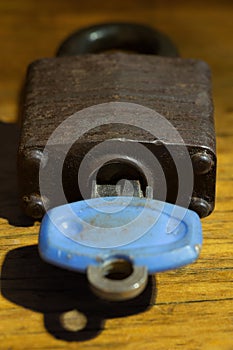 Old rusted padlock with is key on a wood background