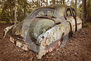 Old rusted scrap car in a forest