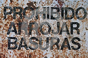 Old rusted sign in black lettering stipulating that littering is prohibited in spanish, prohibido arrojar basuras photo