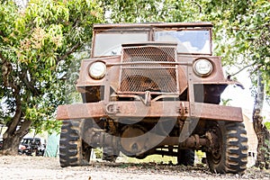 An old rusted wartime Blitz truck left under some trees