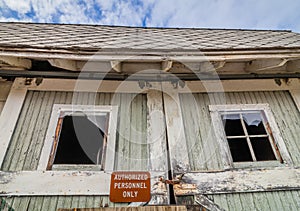 Old rustic abandoned barn with Authorized Personnel Sign on door with broken windows