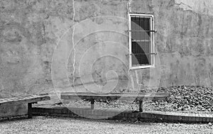 An old rustic alley wall with one solitary barred window.