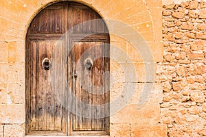 Old brown wooden entrance door and stone wall of mediterranean mansion