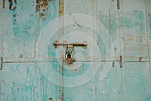 Old rustic door with blue peeling paint, rusty hinges, a  padlock, in Mandawa haveli Rajasthan India