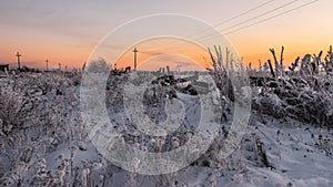 Old rustic fence covered with snow and hoarfrost evening sunset winter landscape cattle corral