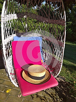 Old rustic hat in swing with pink pillow, romantic