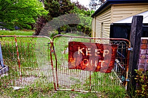 Old rustic keep out sign on metal gate