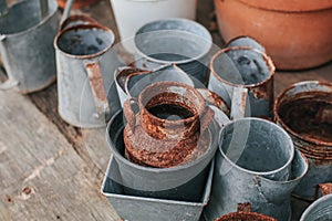 Old rustic metal silver pot and and brown-orange clay pot on a black wooden table outdoor in garden to decorate the house