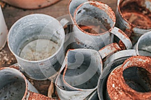 Old rustic metal silver pot and and brown-orange clay pot on a black wooden table outdoor in garden to decorate the house