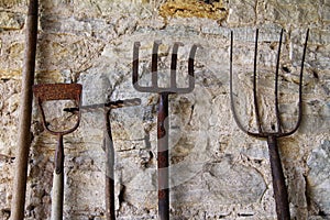 Old rustic tools leaning against a stone wall