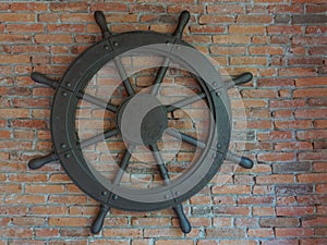 Old rustic vintage iron ship wheel over brick background