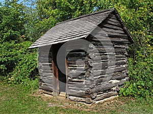 Old rustic wood log outhouse.