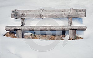 Old rustic wooden bench surrounded by lots of snow