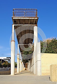 Old rusting abandoned pier with metal railings and concrete columns in paphos cyprus with a sunlit blue sky