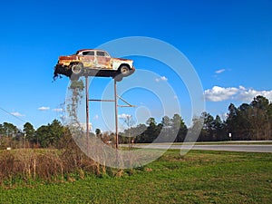 Old Rusting Car On Top Of Poles Roadside