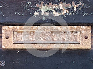 an old rusting chrome letterbox in a blue wooden door with chipped peeling paint with the word correio