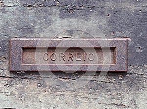 an old rusting iron letterbox in a black wooden door with chipped peeling paint with the word correio photo