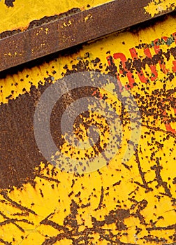 Old rusting metal skip container with yellow pealing paint