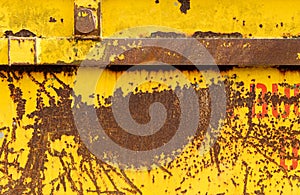 Old rusting metal skip container with yellow pealing paint