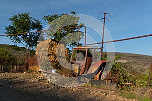 Old rusty and abandoned tractor on the street with some fodder in the background in the town of Azokh part of the Janapar Trail in