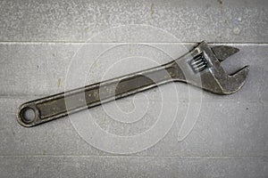 Old rusty adjustable wrench on a metal background. Old style.