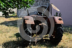 Old rusty agricultural tractor parked on lawn in backyard of Croatian house