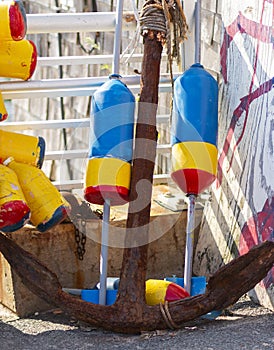 Old rusty anchor with colorful obster buoys