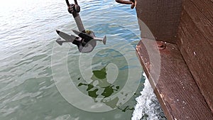 Old rusty anchor hanging rope, staggering near bow of stern floating wooden ship