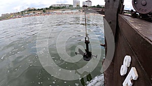 Old rusty anchor hanging rope, staggering near bow of stern floating wooden ship