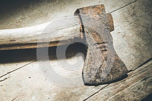 Old rusty axe is lying on rustic wooden floor