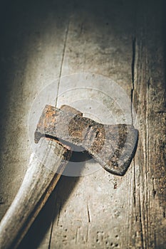 Old rusty axe is lying on rustic wooden floor
