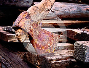 Old rusty axe with rotten haft on wooden boards