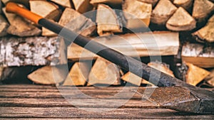 An old rusty axe stands against the woodpile